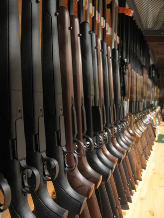 shotguns lined up next to one another along a wall